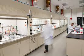 Laboratory with  a wall lined with fume hoods and a blurred person walking past them.