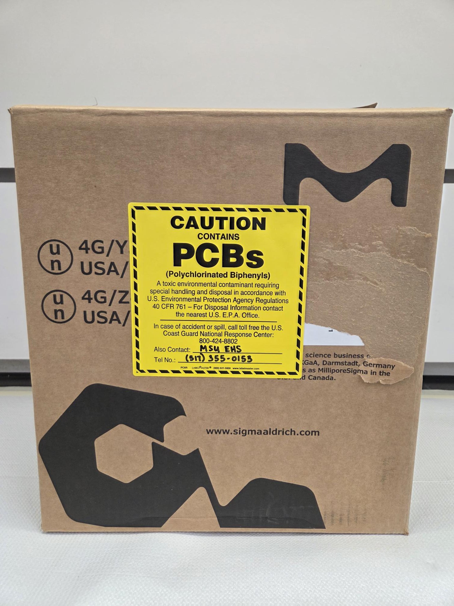 cardboard box with black and yellow PCB label and contact information for MSU EHS