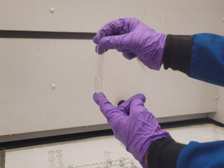 Test tube depicting a clear, unknown liquid floating on top of clear deionized water.